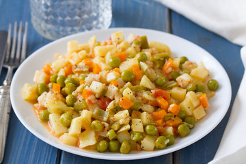 vegetables with fish on white plate and glass of water
