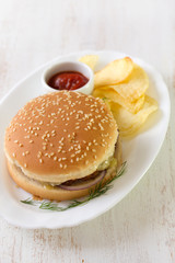 hamburger with chips and sauce on white dish on white wooden background