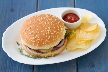 hamburger with chips and tomato sauce on dish