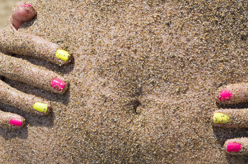 Girl holding her belly covered with sand