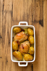 chicken with potato in dish on brown wooden background