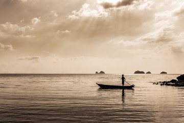Naklejka premium silhouette of Fisherman controls the Fishing boat. sepia toned