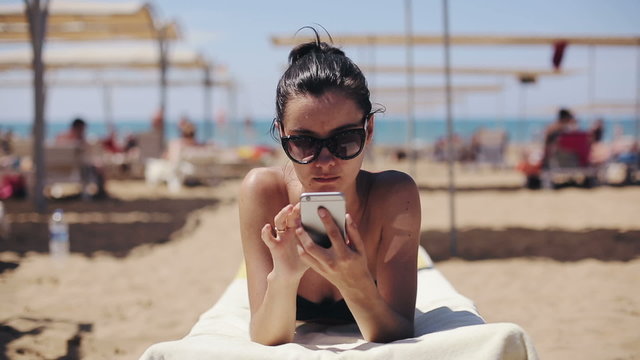 Attractive woman in sunglasses relaxing and using app on smartphone