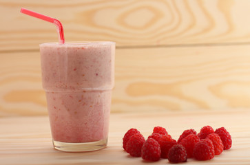 Smoothie from raspberries  in a glass and raspberries  on wooden