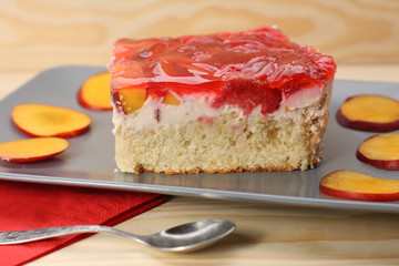 Strawberry and peach cake with gelatin on grey plate on wooden t