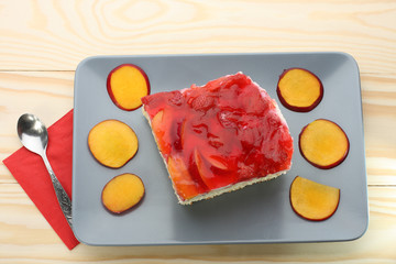 Strawberry and peach cake with gelatin on grey plate on wooden t