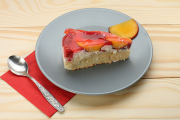 Strawberry and peach cake with gelatin on grey plate on wooden t