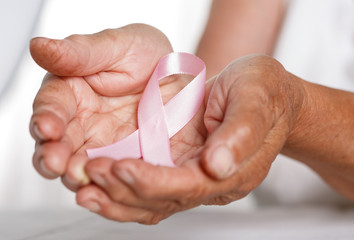 Elder woman hands holding pink breast cancer awareness ribbon