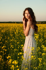 Naklejka na ściany i meble beautiful young woman moving and posing in the rapeseed field