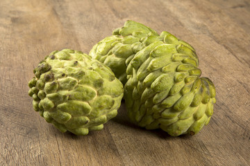 Some Sugar-Apples over a wooden table. Atemóia