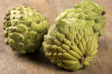 Obraz premium Some Sugar-Apples over a wooden table. Atemóia