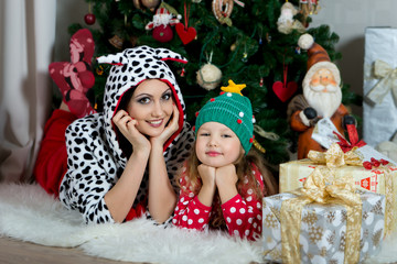 Mother and daughter in festive home clothes under the Christmas tree