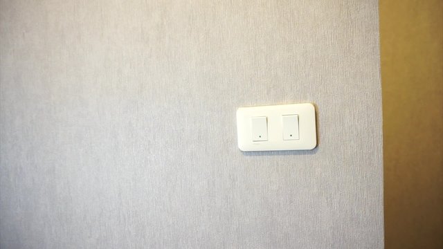 Man turning light on a wall switch