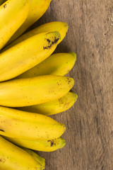 A banch of bananas and a sliced banana in a pot over a table.