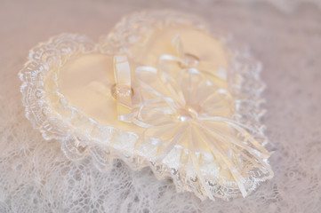 Wedding rings on a cushion with silk and lace decoration