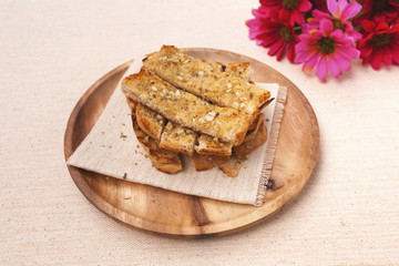 Herbs garlic bread on wooden plate with flower on background