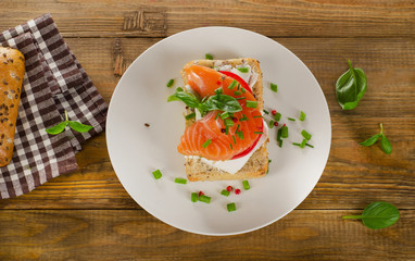 Sandwich with cereals bread and salmon on wooden background.