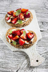 sandwich with strawberries, soft cheese and balsamic vinegar on a light wooden background