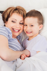 Smiling mother and son laying in bed