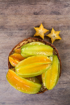 Some caramboles in a basket over a wooden surface