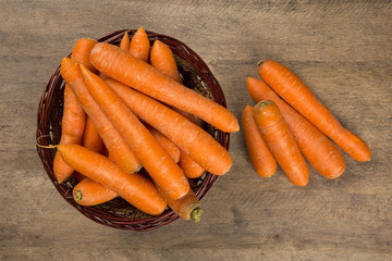 Fresh carrot with green leaves on wooden table