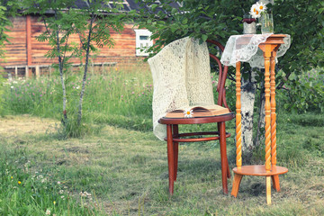 book on a chair in the park with tea and flowers