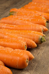 Fresh carrot with green leaves on wooden table