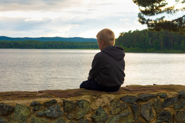sad child sitting at the lake