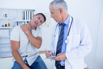 Obraz na płótnie Canvas Doctor looking at patient shoulder 