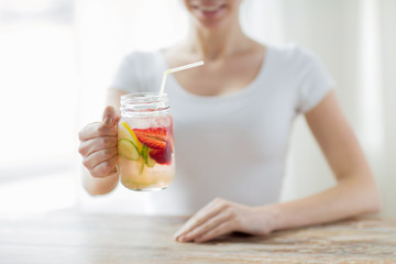 close up of woman holding glass with fruit water