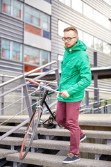 young hipster man carrying fixed gear bike in city