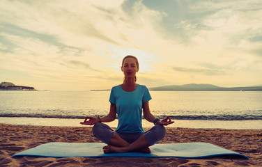 Fototapeta premium Young woman sitting in pose of lotus