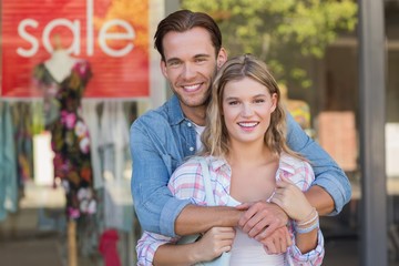 happy couple standing in front of a SALE sign