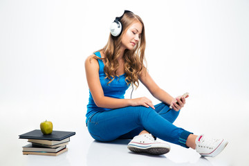 Woman with headphones and using smartphone on the floor