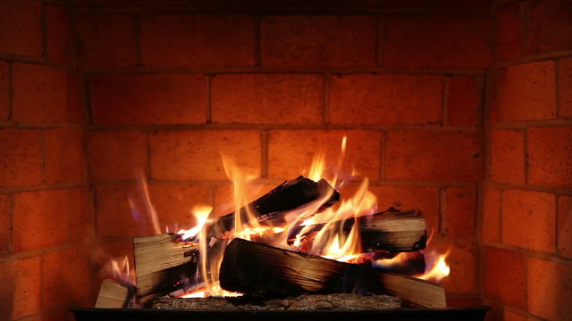 A Real Wood Fire Burning and Glowing Inside a Clean Brick Fireplace.