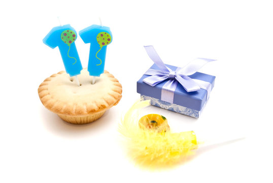 cupcake with eleven years birthday candle, gift and whistle on w