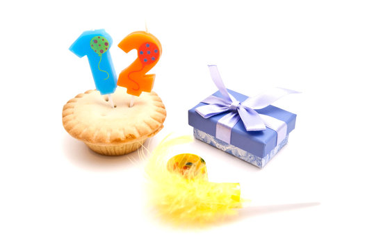 cupcake with twelve years birthday candle, gift and whistle on w