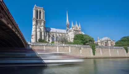 Notre dame and Seine river, blurred tourist boat, long exposure