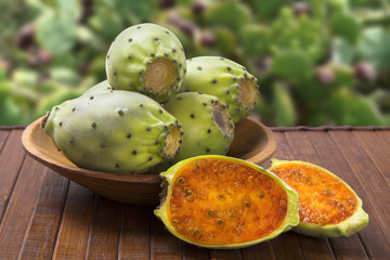 A couple of Figs of India in a wooden pot over a wooden surface.