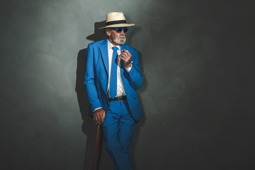 Senior Businessman with Cane Leaning Against Wall