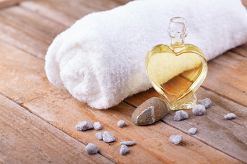 Natural spa still life with massage oil and white towel on wood