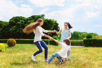 Fototapeta premium Happy Mother with daughter and son playing on grass smiling