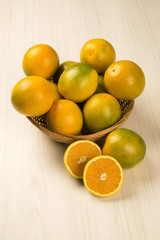 Close up of some oranges in a basket over a wooden surface