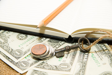 Opened notebook, pencil, key and money on the old tissue