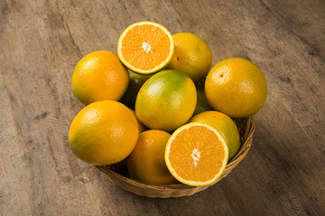 Close up of some oranges in a basket over a wooden surface