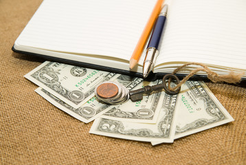 Opened notebook, pencil, pen,  key and money on the old tissue