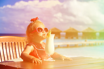 Obraz na płótnie Canvas little girl drinking cocktail on tropical beach