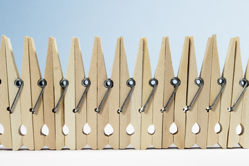 A "fence" formed by spring-type wooden clothespins on white floor and blue background