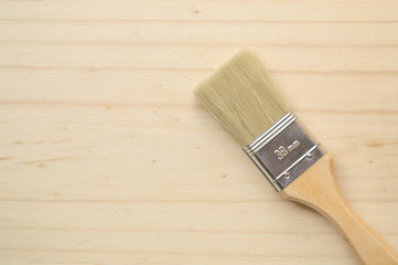 Painter's brush isolated on wooden background. Copyspace on the left side.