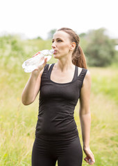 Young woman drinks water after making sport exercises